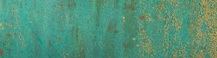 Cracked turquoise paint on cement with scattered cracked yellow paint