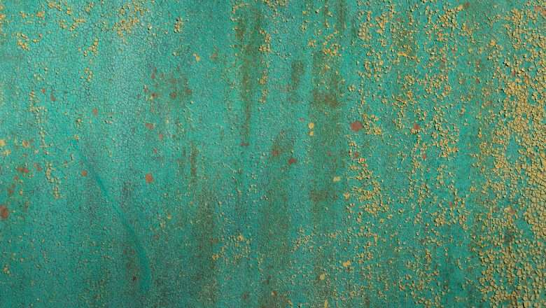 Cracked turquoise paint on cement with scattered cracked yellow paint