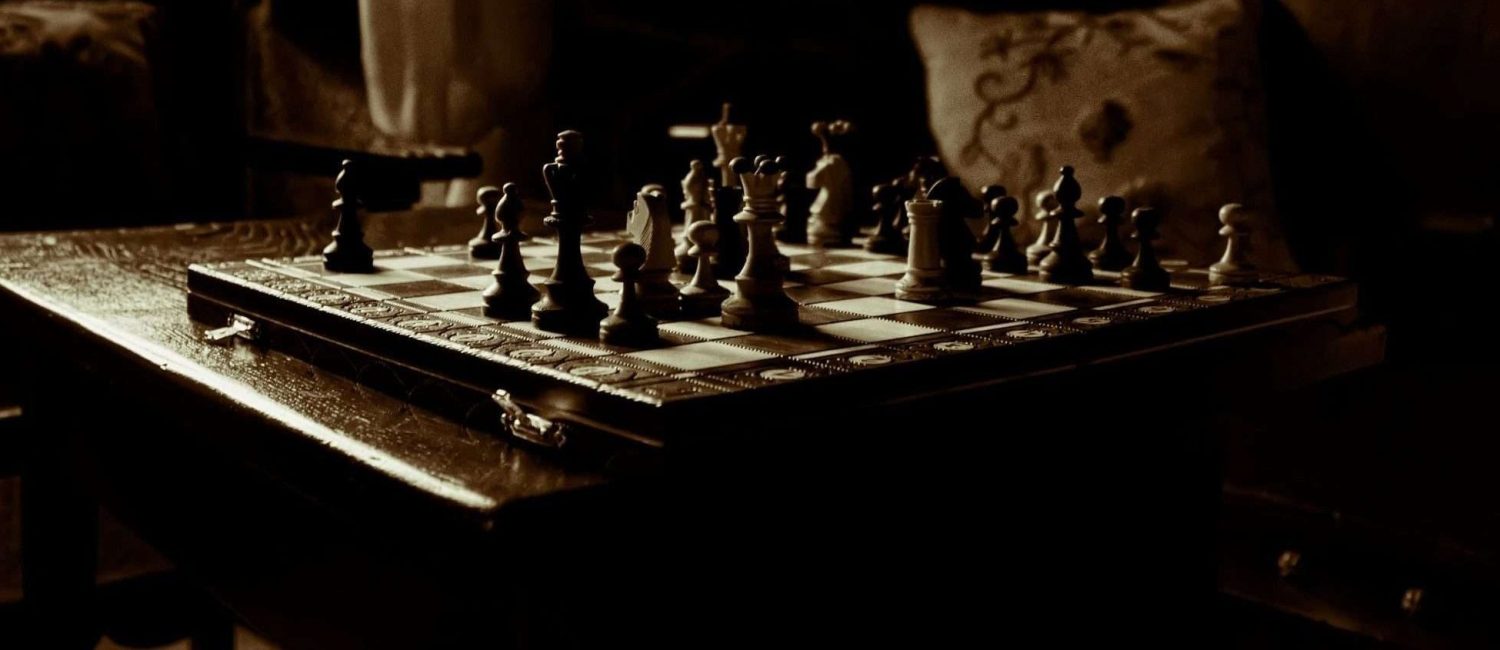 Sepia-toned photo of chessboard in light by window - Photo by Javier Grixo via Unsplash